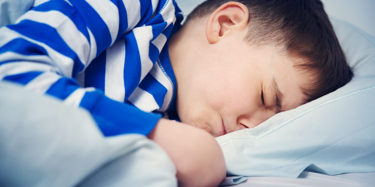 Boy sleeping in bed in pajamas Boy sleeping in bed in pajamas. Child lying in bed on pillow at night
